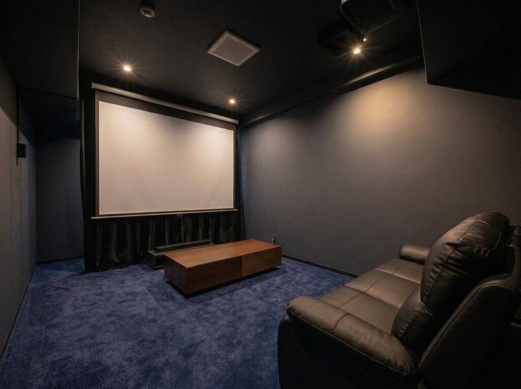 大きなスクリーンと革のソファが置かれた小さなシアタールーム。貸切のプライベートシアター